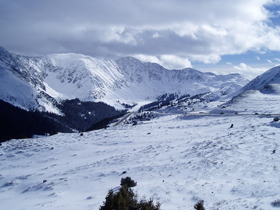 Snowy mountain range with a road and vehicles.