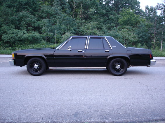 Black full-size four-door sedan in side profile on pavement