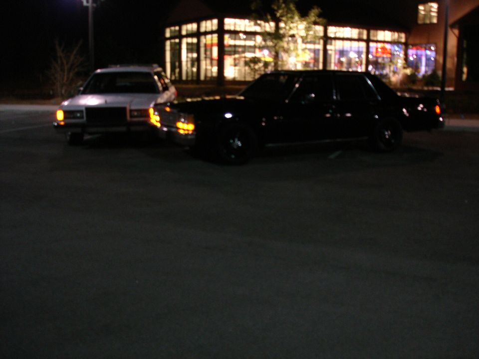 Two sedans parked at night in front of a building.