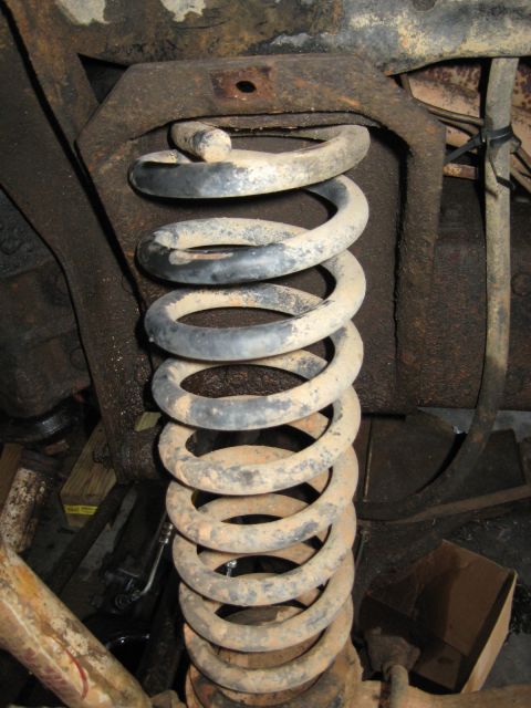 1978 Ford Bronco - Photograph of a coil spring in the front suspension under a vehicle, not a technical document.