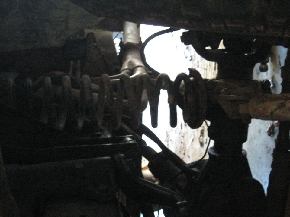 Dark underbody view of coil springs and axle components of a vehicle