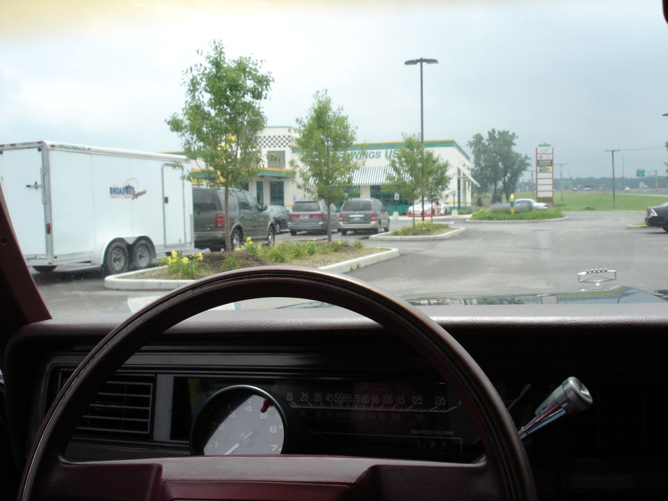 View over red dash and steering wheel to horizontal speedometer and added round gauge