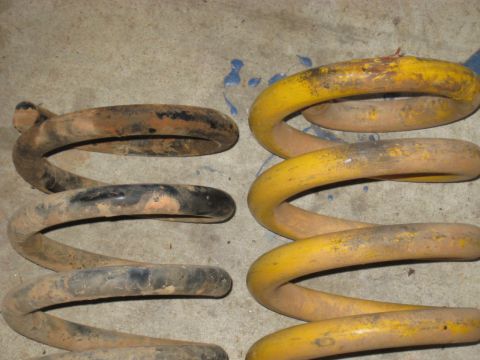 1978 Ford Bronco - Photograph comparing a worn coil spring with a yellow aftermarket spring, not a technical document.