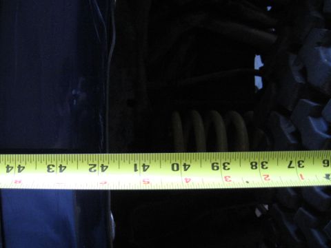 1978 Ford Bronco - Photo of a tape measure laid across a vehicle's body panel and rear coil spring, not a technical document.