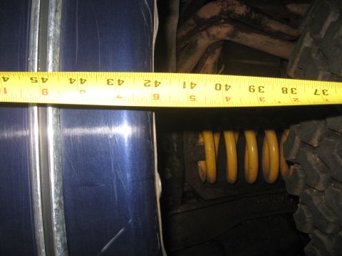 1978 Ford Bronco - Photo measuring a vehicle body panel and yellow coil spring with a tape measure, not a technical document.