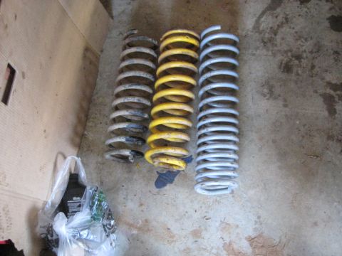 1978 Ford Bronco - Photo comparing three vehicle coil springs on a concrete floor, not a technical document.