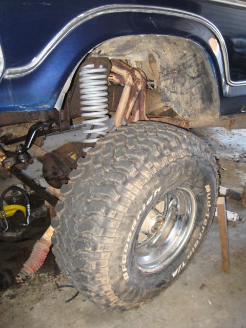 1978 Ford Bronco - Photo of a truck's front suspension showing a coil spring and mounted mud tire, not a technical document.