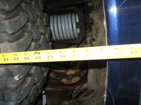 1978 Ford Bronco - Photo measuring under a vehicle near a coil spring with a tape measure, not a technical document.