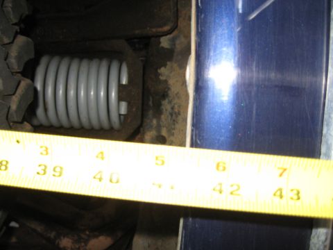 1978 Ford Bronco - Photo of a tape measure under a vehicle alongside a coil spring, not a technical document.