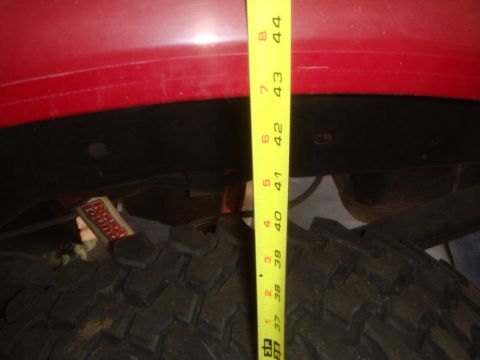 1992 Ford Bronco - A yellow measuring tape is placed against the fender of a red vehicle, showing a measurement of approximately 41.5 inches. A portion of a l…