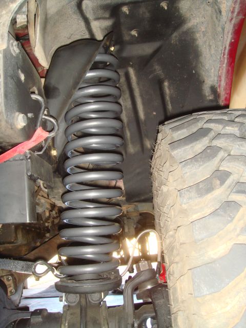 1992 Ford Bronco - A close-up view of the suspension system of a vehicle, featuring a large gray coil spring and a portion of a large, knobby tire. The spring…
