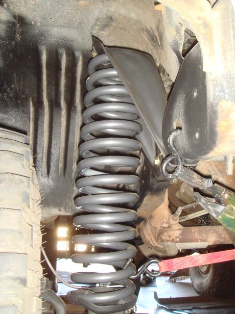 1992 Ford Bronco - A close-up view of the suspension system of a 1992 Ford Bronco, focusing on the front coil spring and surrounding chassis components.