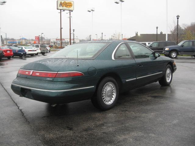 Dark green 1994 Lincoln Mark VIII coupe, rear passenger side view, wet asphalt lot