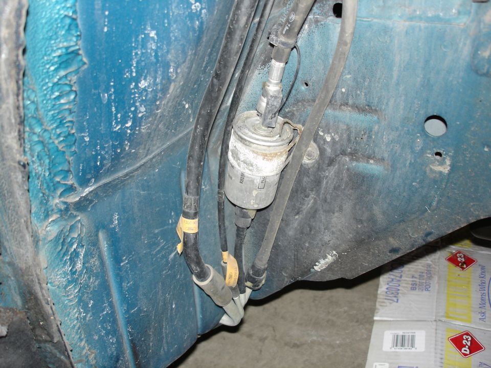 Fuel filter assembly with hoses on underside of blue vehicle.