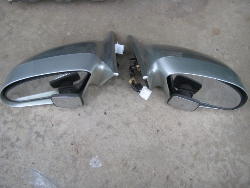 Pair of grey and silver car side view mirrors on concrete