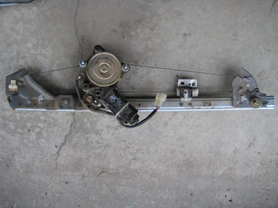 Car power window regulator assembly with motor and cable on concrete.