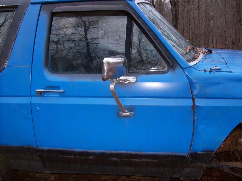 Blue Ford Bronco driver's side door and window with side mirror