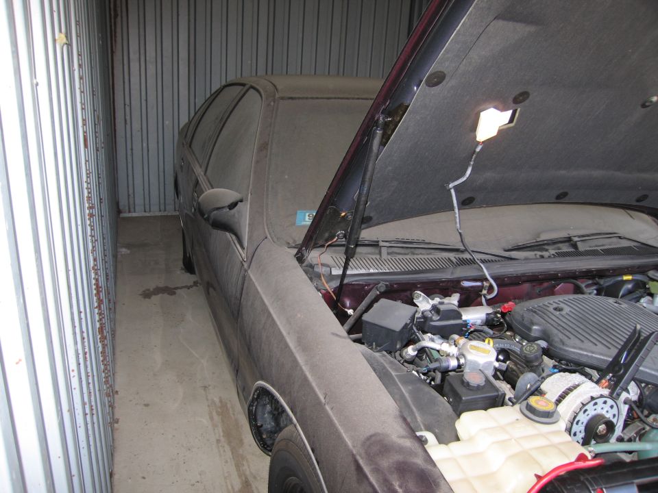 Maroon sedan parked in a storage container with hood raised