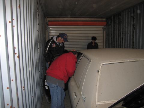 1991 Ford LTD Crown Victoria - Photograph of people examining a stored car, not a technical document.