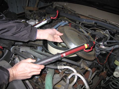 1991 Ford LTD Crown Victoria - Photograph of hands working on the air cleaner in an engine bay, not a technical document.