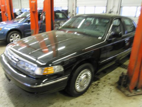 1991 Ford LTD Crown Victoria - Photograph of a black Ford Crown Victoria front three-quarter view in a service shop, not a technical document.