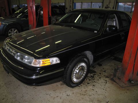 1991 Ford LTD Crown Victoria - Photograph of a black Ford Crown Victoria in a service bay near a lift, not a technical document.