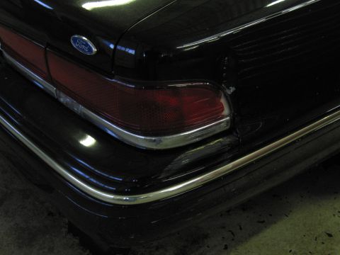 1991 Ford LTD Crown Victoria - Close-up photograph of a black Ford sedan taillight and rear bumper, not a technical document.