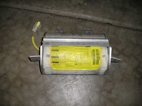 1986 Toyota Hilux - A car airbag module with a yellow warning label is shown lying on a concrete floor. A yellow electrical connector is attached to the module.