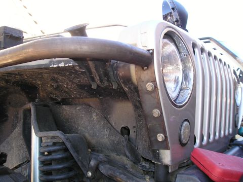 1986 Toyota Hilux - A close-up, low-angle view of the front fender and grille area of a modified Jeep Wrangler. A large metal tube, likely part of a custom bum…