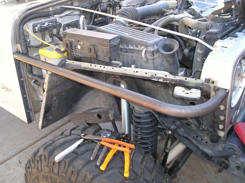 Jeep engine bay and tire with roll cage tube and tools.