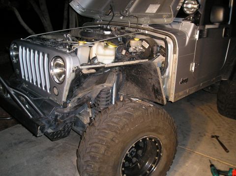 1986 Toyota Hilux - The front passenger side of a silver Jeep Wrangler is shown with the hood open, revealing the engine bay. The vehicle has a large aftermark…