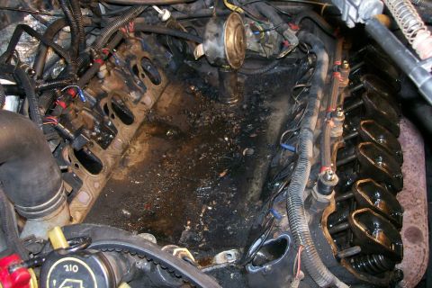 1992 Ford C-350 (Centurion Conversions) - Engine bay with significant oil leaks and grime. Components like valve covers and wiring are visible.