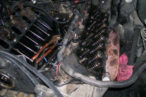 1992 Ford C-350 (Centurion Conversions) - Close-up view of an engine with its valve covers removed, revealing the internal mechanics and some tools.