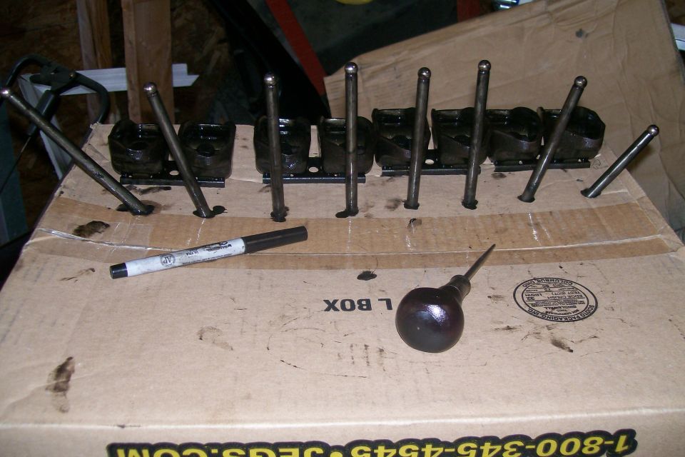 Engine valve train components laid out on a cardboard box with a marker and oil can
