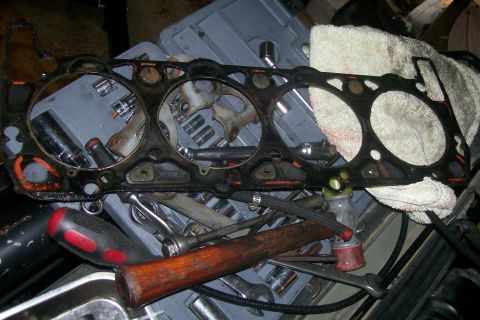 1992 Ford C-350 (Centurion Conversions) - A used cylinder head gasket lies on a workbench with various tools and a rag.
