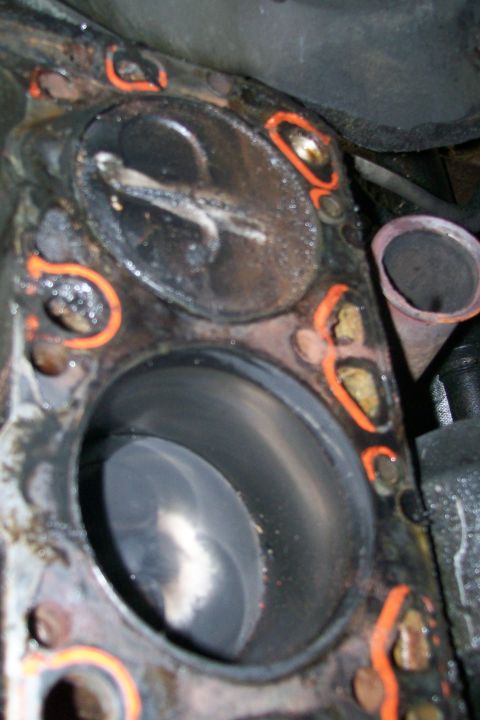 1992 Ford C-350 (Centurion Conversions) - Close-up of a damaged engine cylinder and head gasket, showing wear and orange sealant.