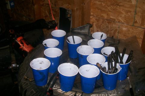 1992 Ford C-350 (Centurion Conversions) - Engine components are organized in blue cups, resting on a tire in a workshop.