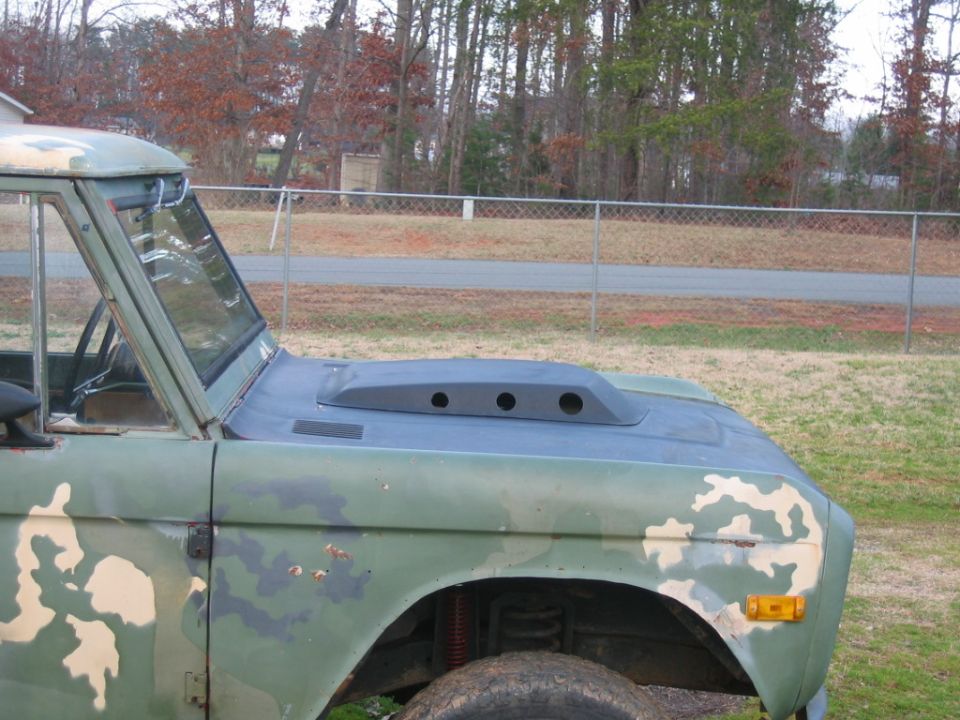 Camouflaged Ford Bronco with a hood scoop and visible suspension