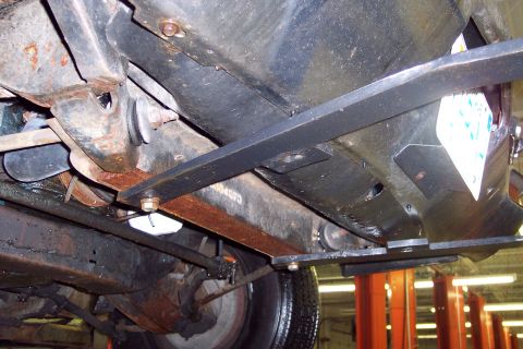 2001 Ford Crown Victoria - The underside of a 2001 Ford Crown Victoria reveals significant rust on its frame and suspension components.