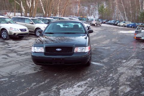 2001 Ford Crown Victoria - A dark 2001 Ford Crown Victoria is parked in a lot with other vehicles, on a cold day.