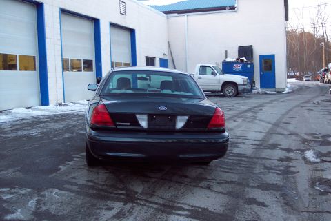2001 Ford Crown Victoria - A dark Ford Crown Victoria is parked in front of a commercial building with a white pickup truck in the background.