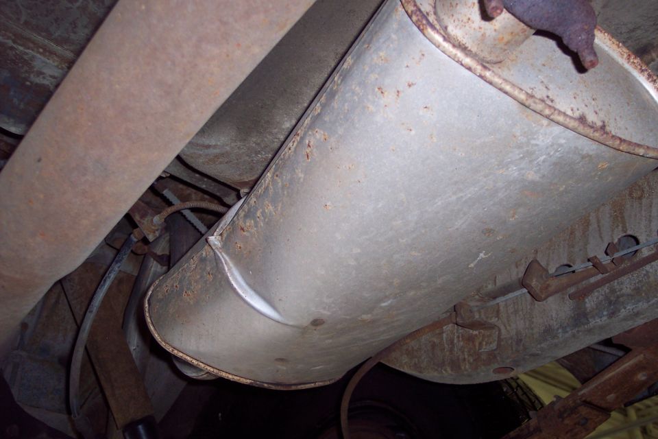 Underside of a vehicle showing rusted exhaust system components.