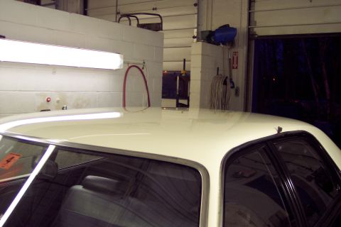 2001 Ford Crown Victoria - A white car's roof and interior are visible inside a garage, with a red sticker on the window.