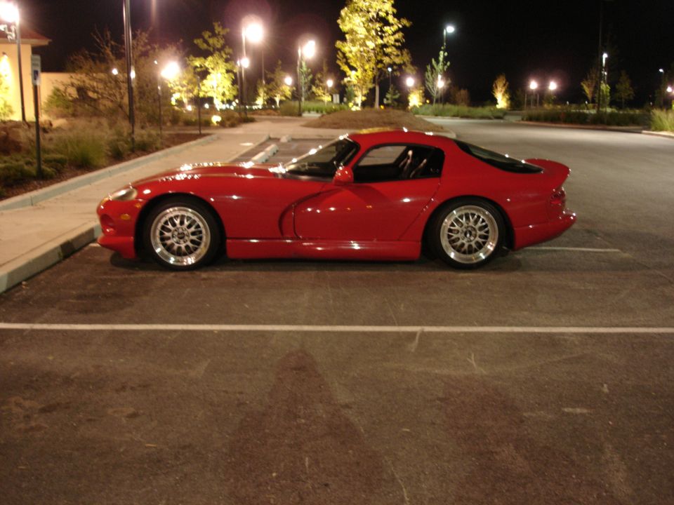Red Dodge Viper parked at night, side view.