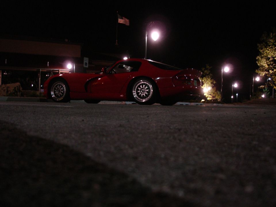 Red Dodge Viper parked at night, low angle shot showing side profile and rear wheel.