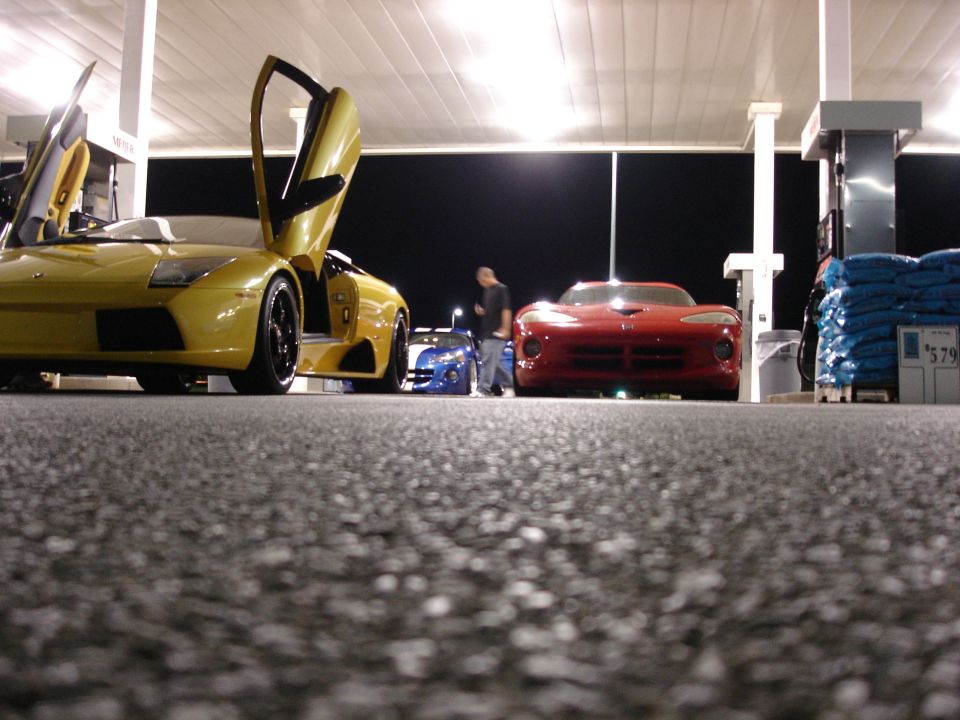 Red Dodge Viper parked at a gas station at night.
