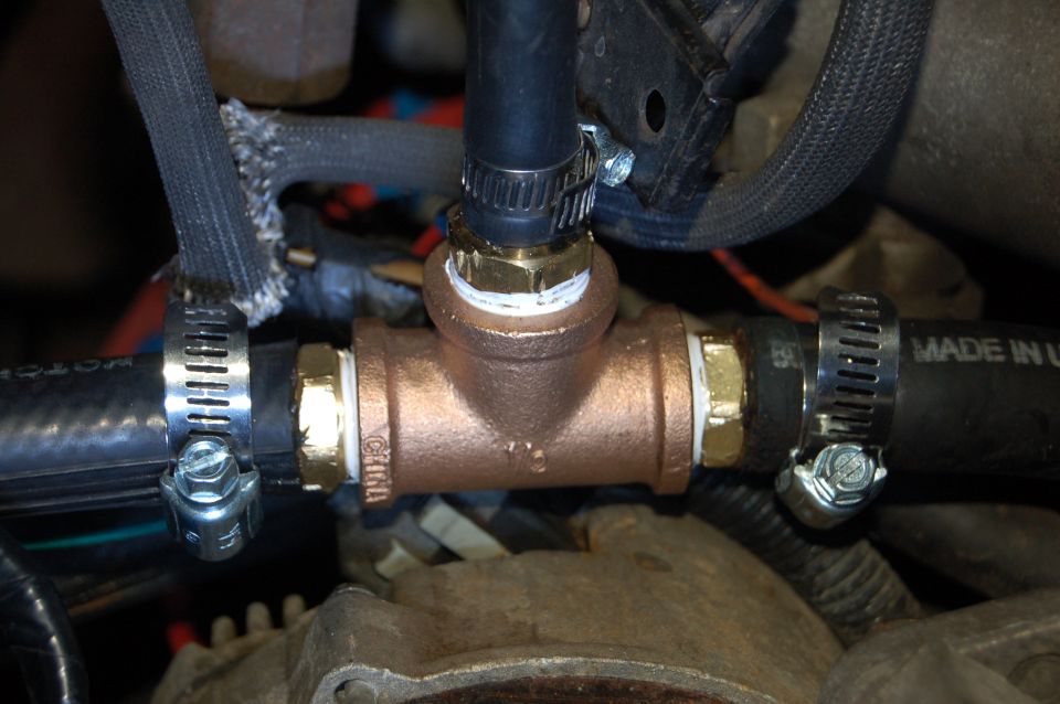 Bronze T-fitting connecting two black hoses with metal hose clamps.