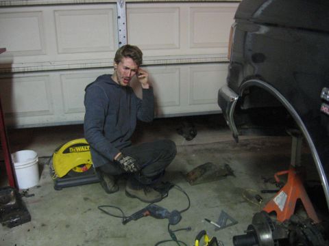 1989 Ford Bronco - A man works on a black 1989 Ford Bronco in a garage, with tools and parts scattered around.