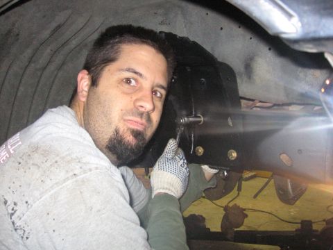 1989 Ford Bronco - A mechanic is seen working on the frame of a vehicle, likely during an installation or repair.