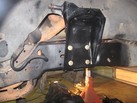 1989 Ford Bronco - A close-up view of a newly painted suspension component on a vehicle's frame, held up by a jack stand.